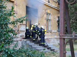 tűzoltók állnak az égő ajtó előtt